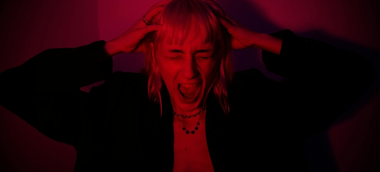 A screaming woman is holding her head and having a panic attack.
