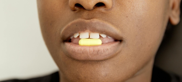 A woman is holding an Ecstasy pill in her mouth.