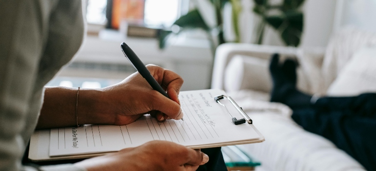 A therapist is sitting in the chair and writing in her notebook.