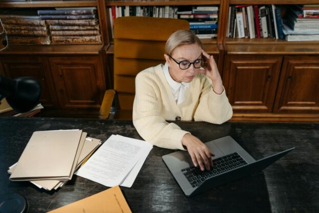 A worried woman is sitting and looking at her computer.