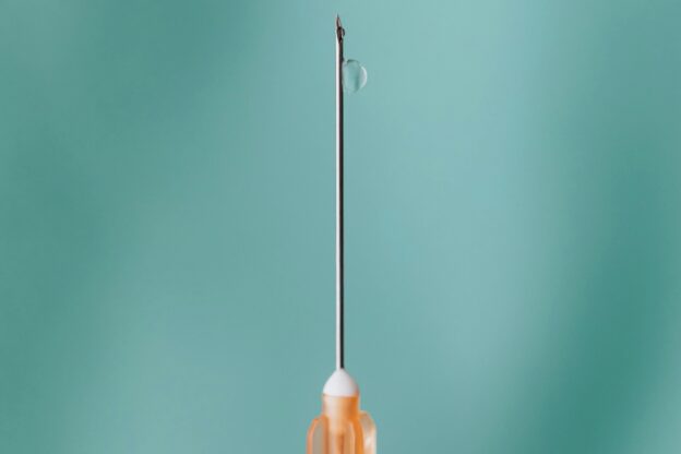 Needle up close on a green surface.