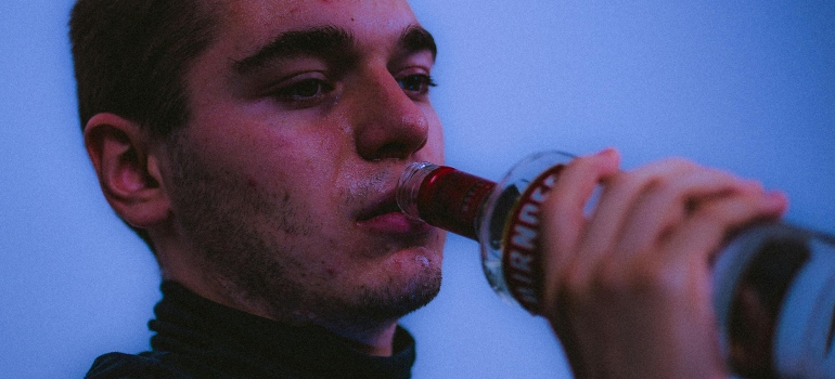 A man is drinking alcohol from a bottle.