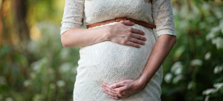 A pregnant woman is holding her belly, and wondering about fetal alcohol syndrome statistics.