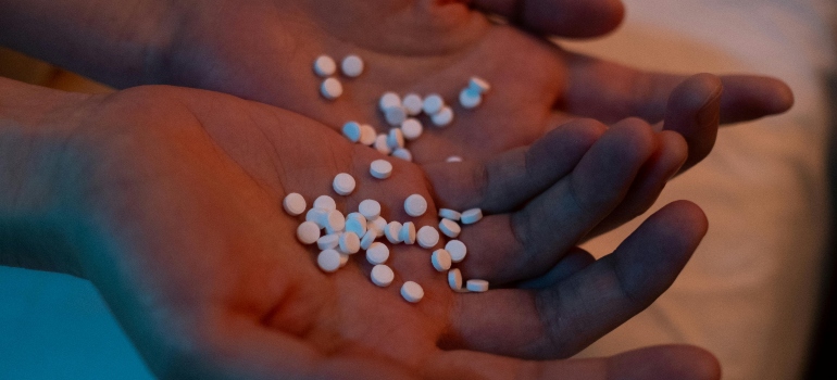 A woman is holding a bunch of pills in her palms.