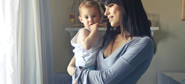 A woman is standing, holding her baby, and thinking about fetal alcohol syndrome statistics.