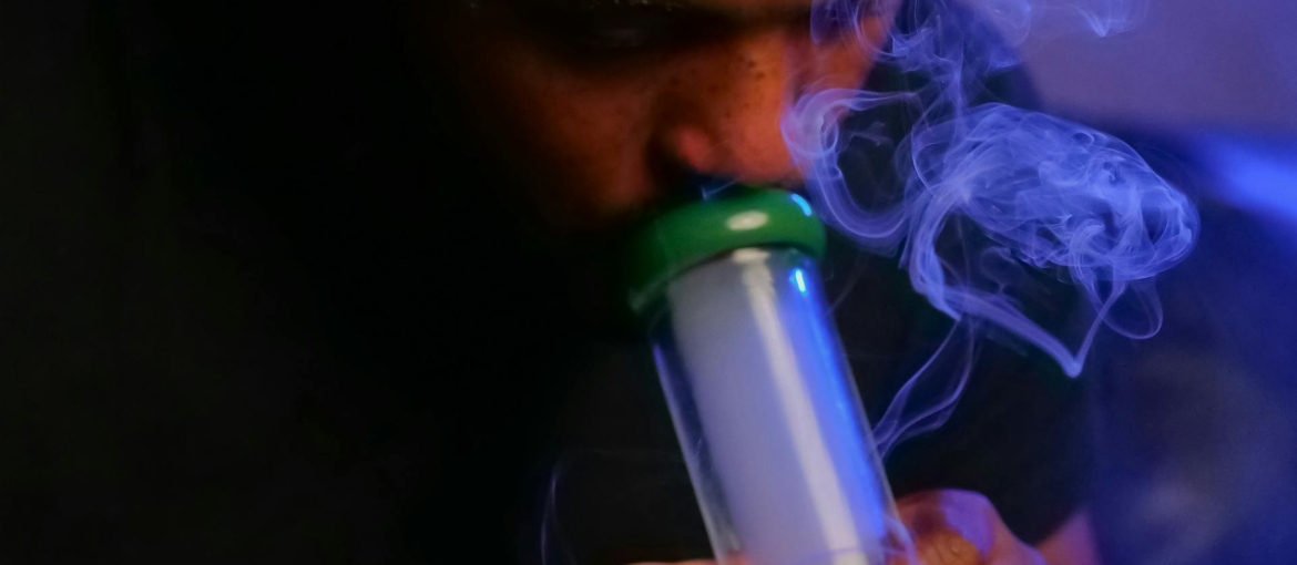 A man is inhaling drugs through the pipe.