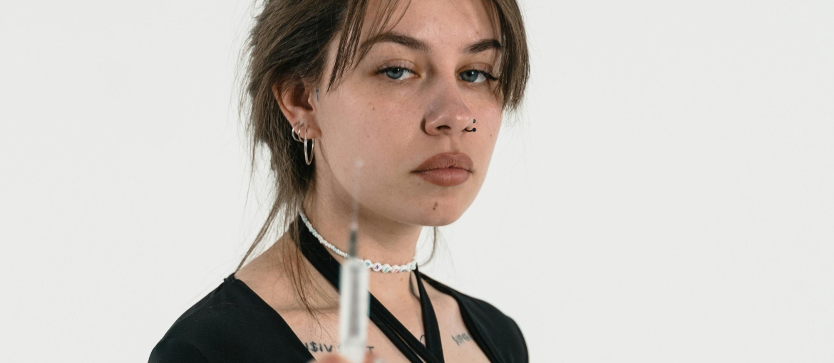 A woman in a black blouse is holding a needle in her hand, and thinking about how to prevent skin and soft tissue infections in injecting drug users.