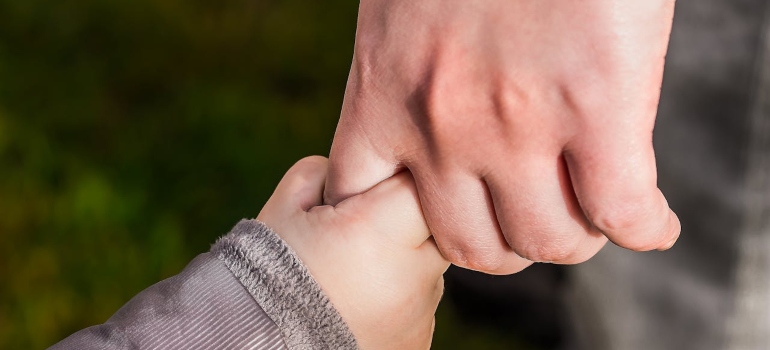 a drug addicted parent holding a child´s hands
