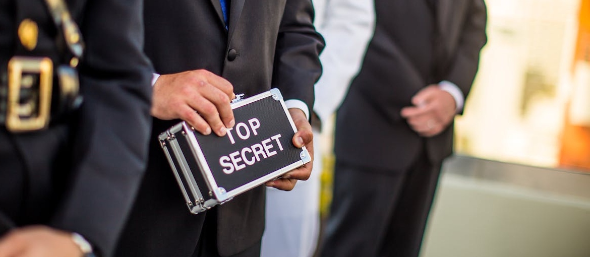 Men in suits holding a ¨top secret¨ sign.