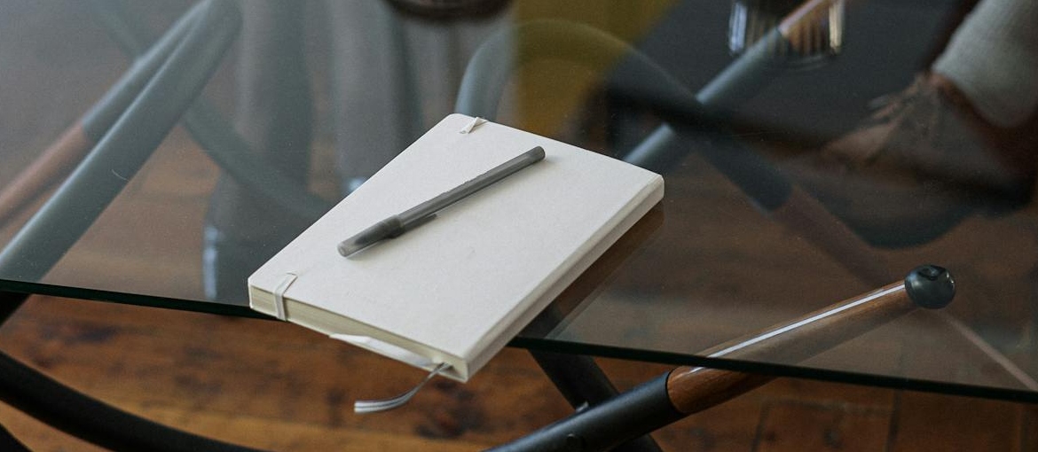 Notebook sitting on a glass table.