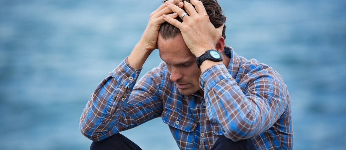 A man holding his hands on his head because he has hydrocodone withdrawal symptoms