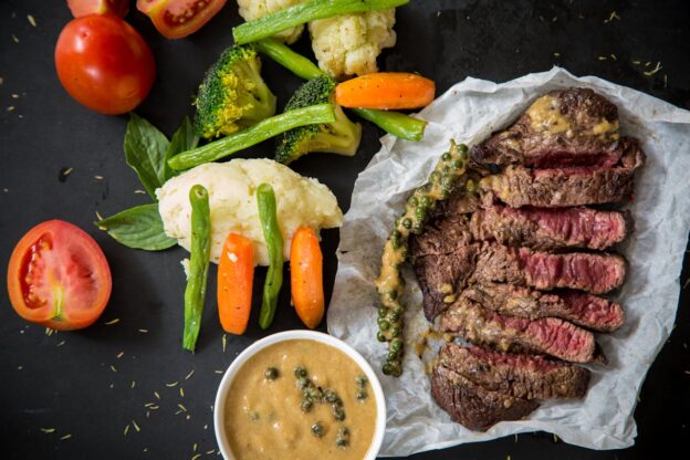 Steak next to cut up vegetablet.