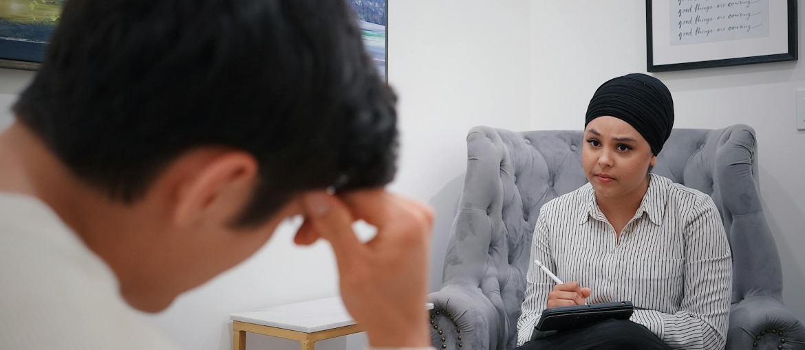 A woman is sitting on the sofa, looking at the man and considering options PHP vs Inpatient treatment.
