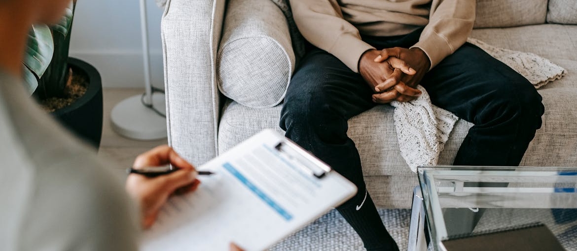 Woman writing in a clipboard while talking to a patient.