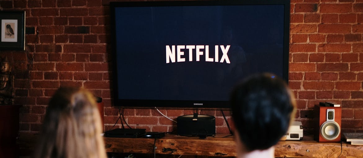 Couple sitting on a couch and watching Netflix.