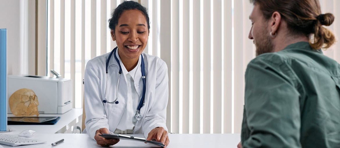 A smiling doctor in a white coat discussing cocaine withdrawal and cocaine treatment with a patient