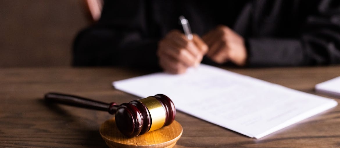 Wooden gavel in front of a judge signing a document.