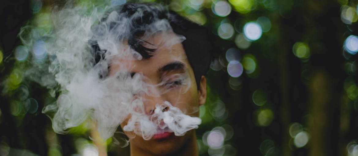 A man covered with smoke while smoking a cigarette.