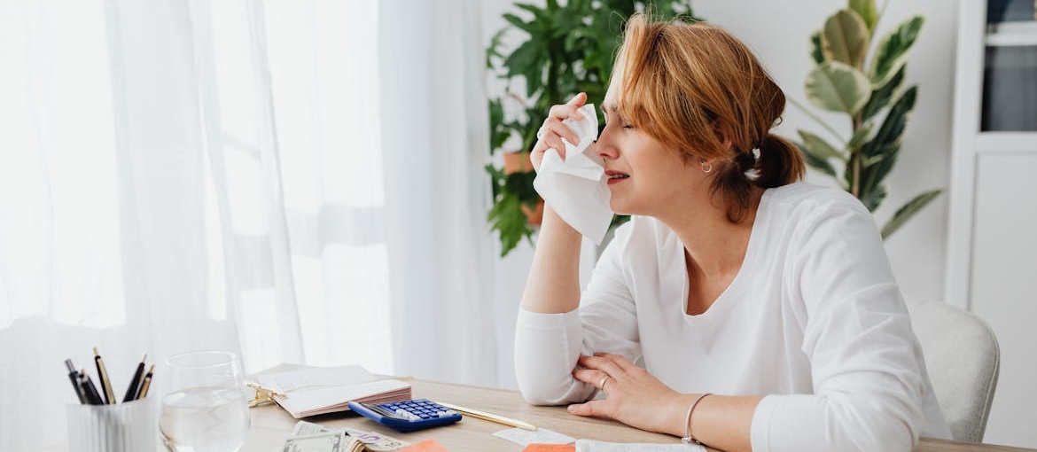 Woman wiping her tears after looking at her bills.