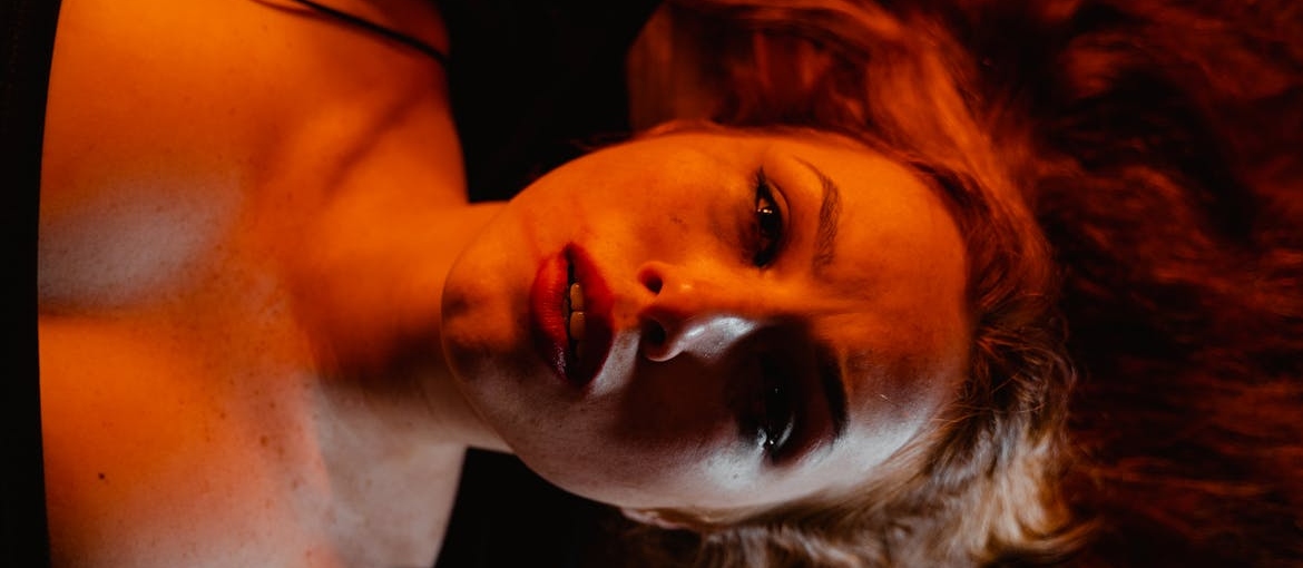 A scared woman is lying and looking up.