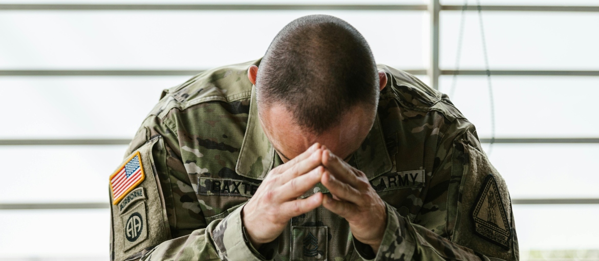 A soldier holding hands on his head thinking about what is the role of environmental factors in addiction.