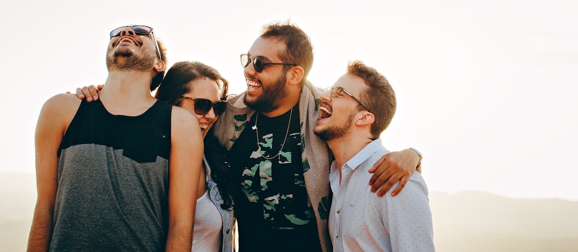 Four friends hugging and laughing.