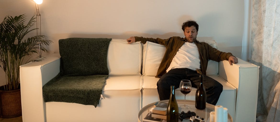 Man sitting on the couch and drinking wine.