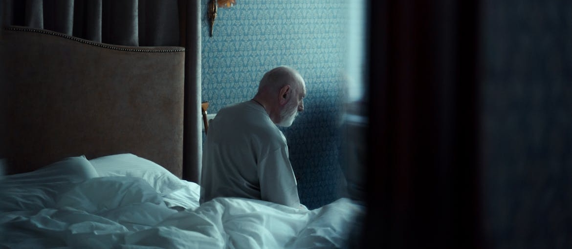 Man sitting on his bed thinking about the link between chronic pain and addiction in older adults.