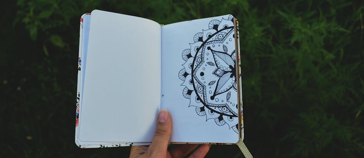 Person holding a notebook with a doodle drawn on it.
