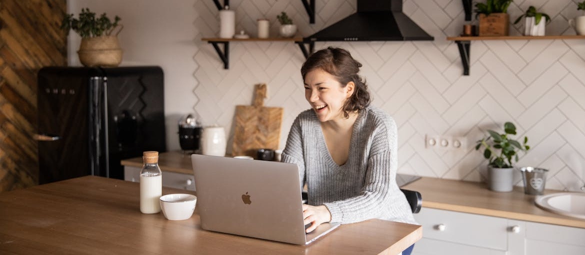 Woman looking at her laptop in her kitchen.