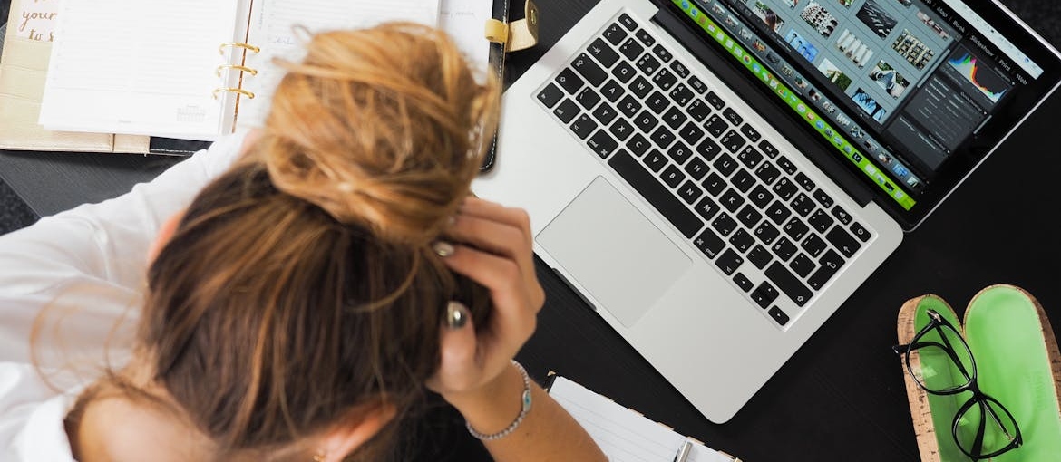 Stressed woman holding her head while looking at her laptop.