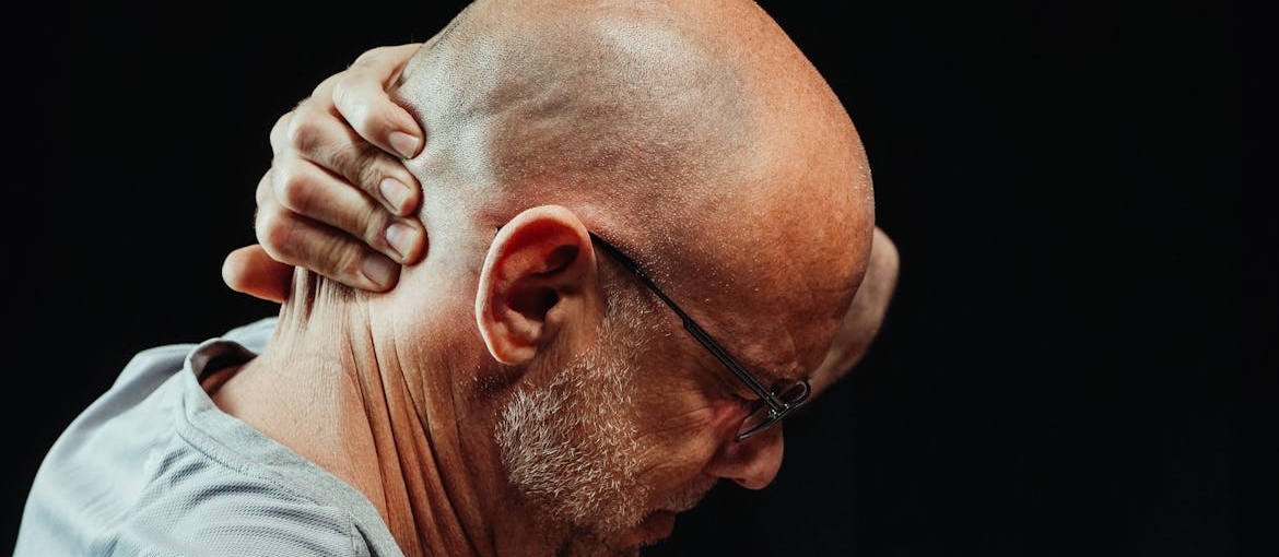 Man holding his neck and scrunching his face.