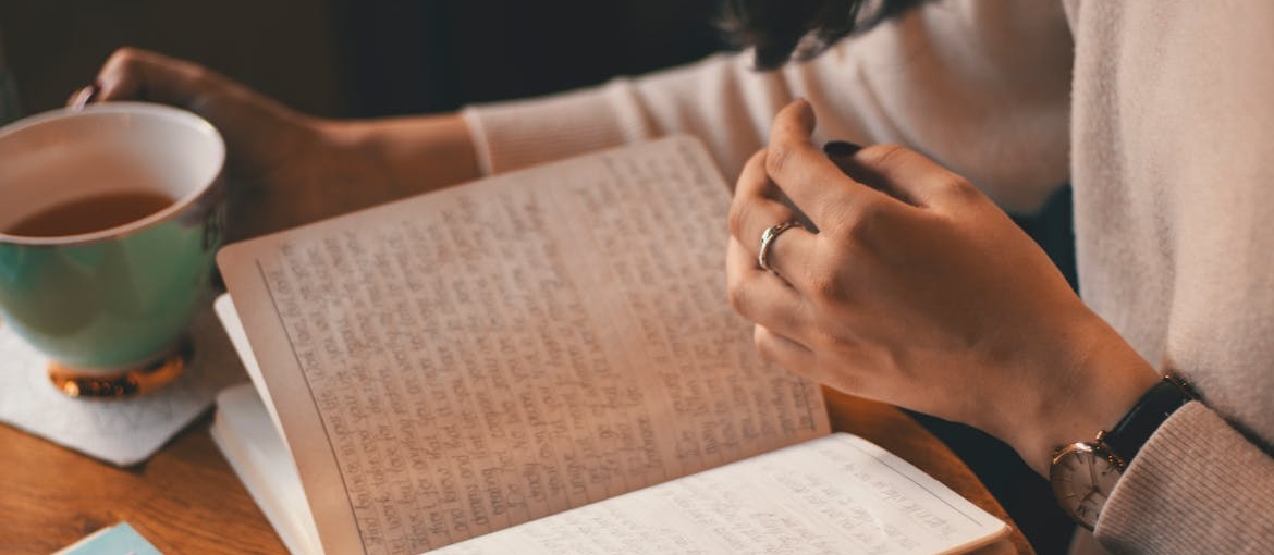 Woman drinking tea and visual journaling in addiction recovery.