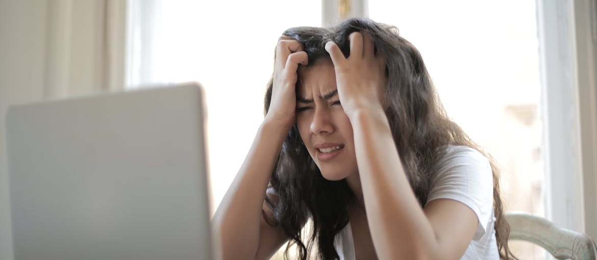 Functioning addict in the corporate world holding her hair while looking at her laptop.