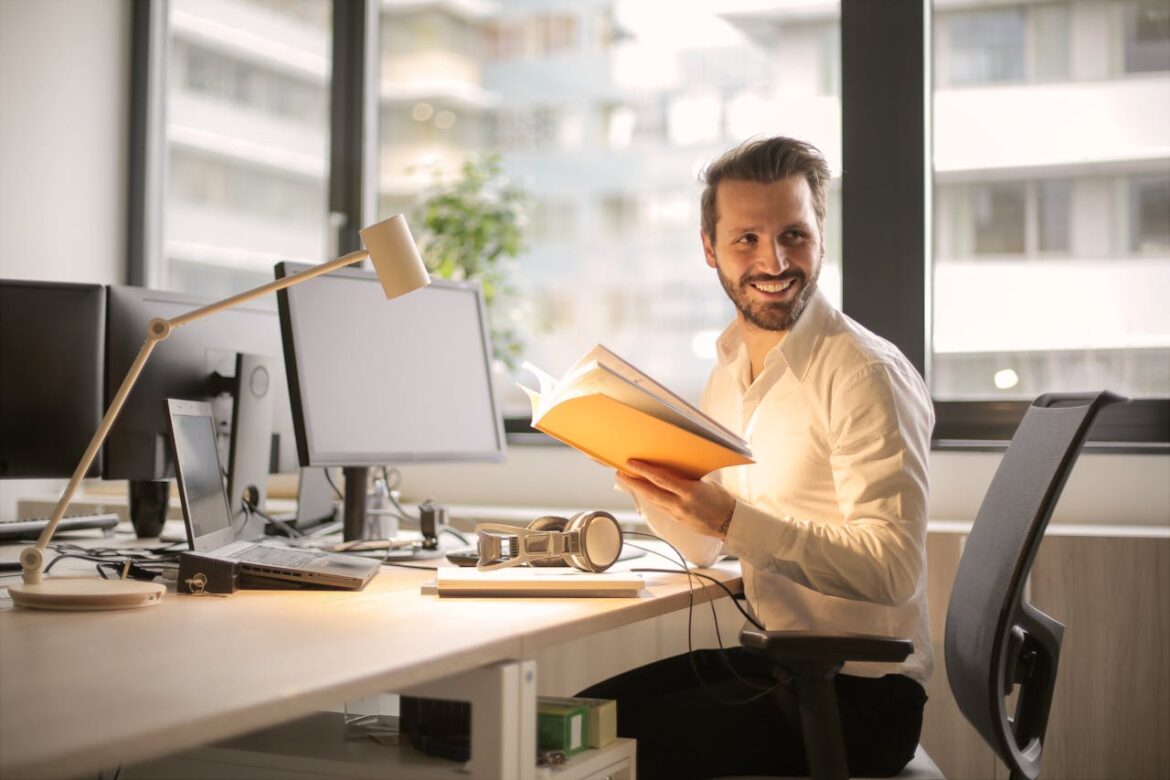 Functioning addict in the corporate world smiling and holding a book.