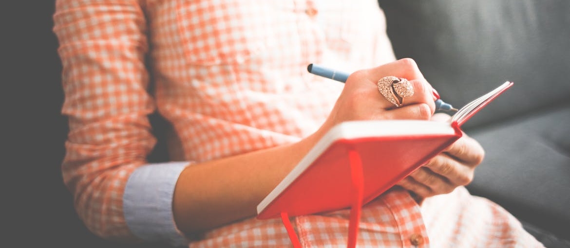 Woman writing in a notebook and visual journaling in addiction recovery.