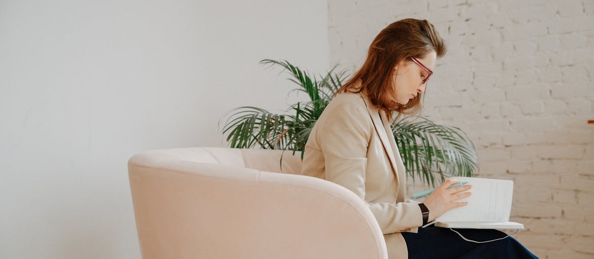 Woman sitting in an armchair and visual journaling in addiction recovery.