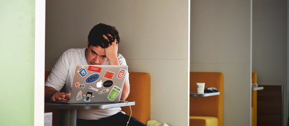 Functioning addict in the corporate world sitting at a booth and working on his laptop.