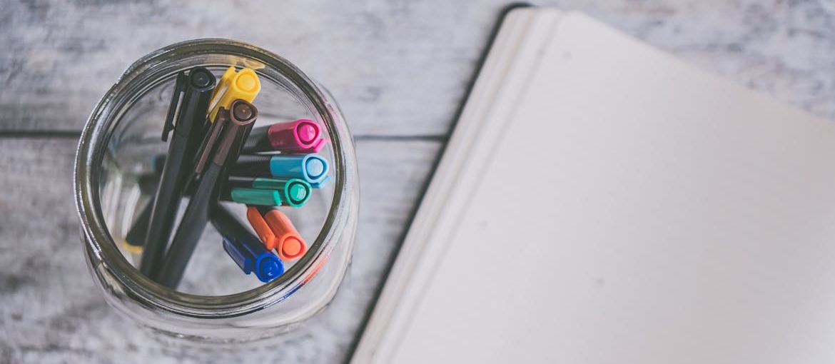 Notebook next to a jar with markers.