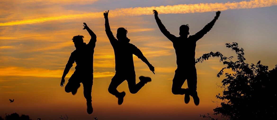 Silhouettes of three men jumping.