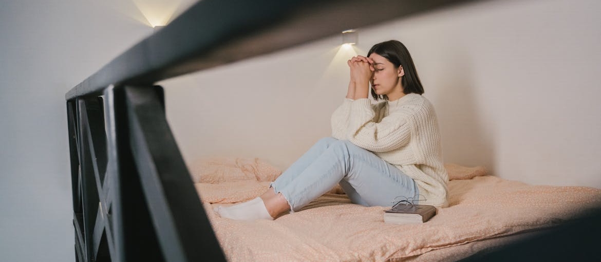 Woman sitting on the bed and praying.