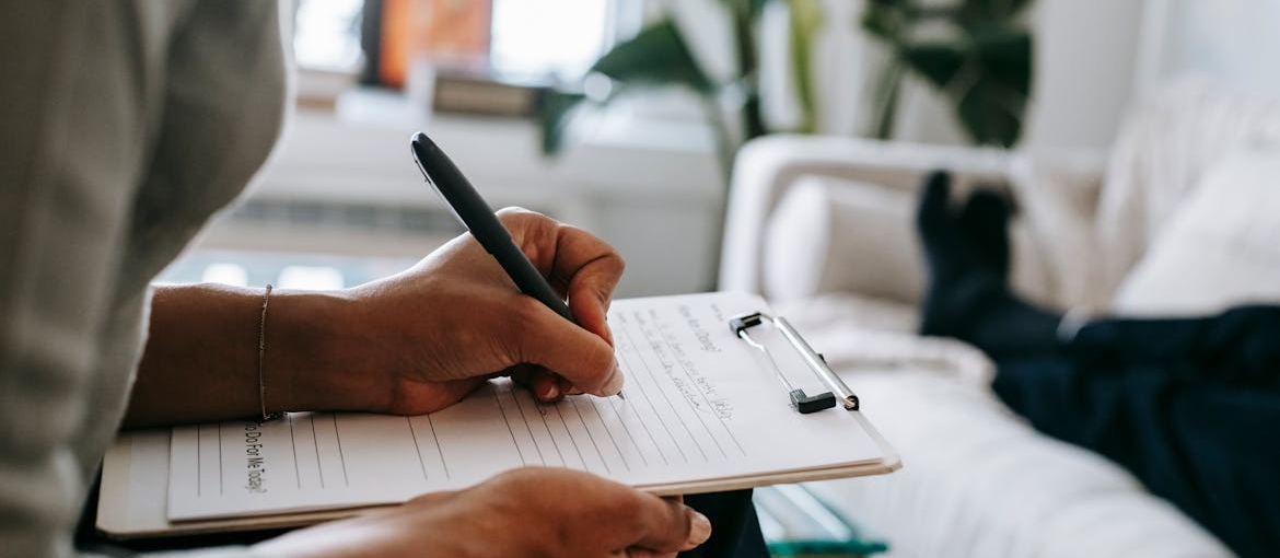 Doctor writing in a clipboard while talking to a patient.