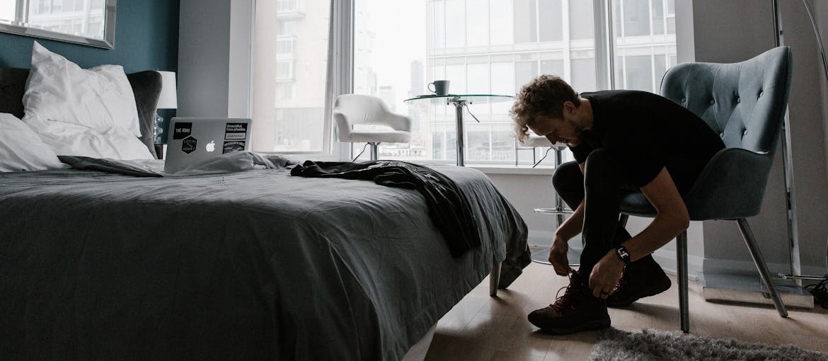Man sitting on a chair and tying his shoes.