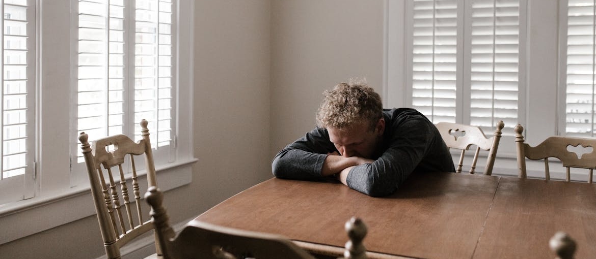 Man sitting at a table and experiencing mental health challenges first responders face.