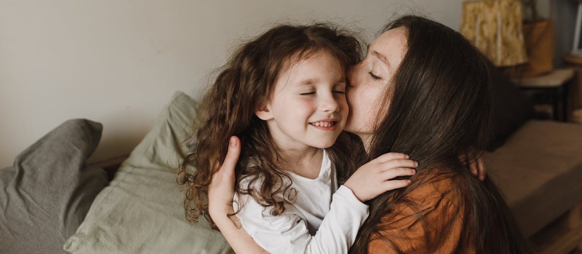 Mother kissing her young daughter on the cheek.