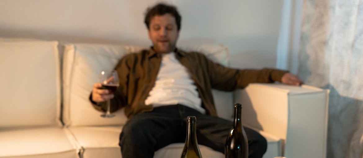 Man drinking wine on his couch while experiencing burnout in first responders.