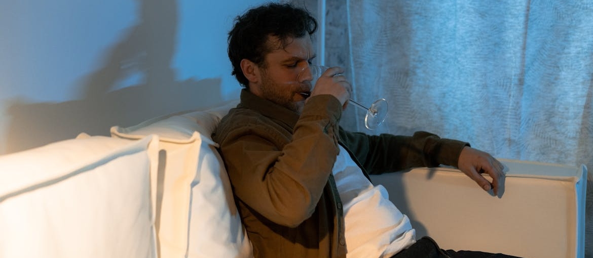 Man sitting on the couch and drinking a glass of wine.