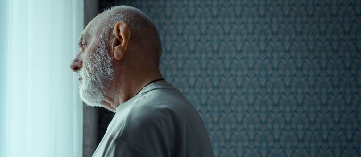 Man looking out of the window and experiencing emotional numbness in recovery.
