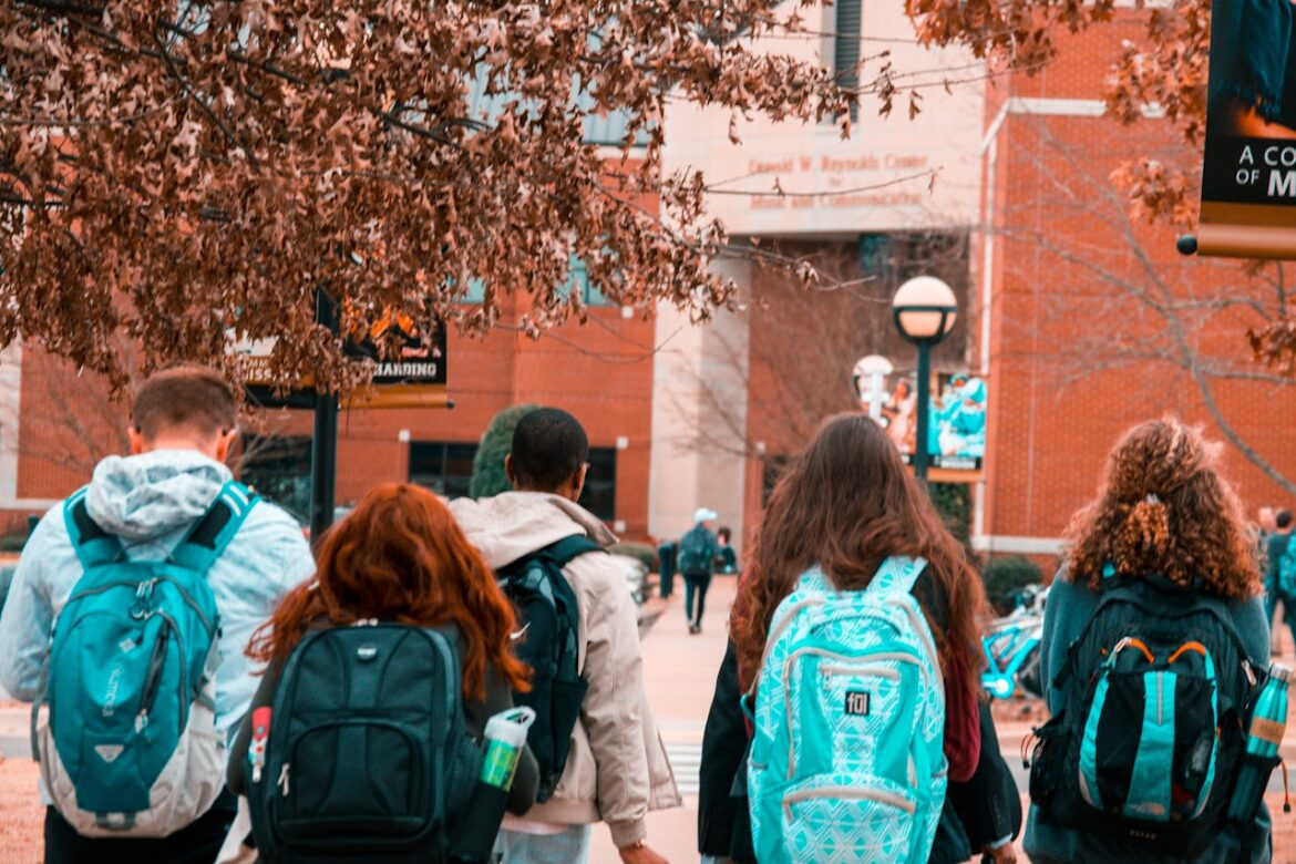 Four students walking towards the college entrance.
