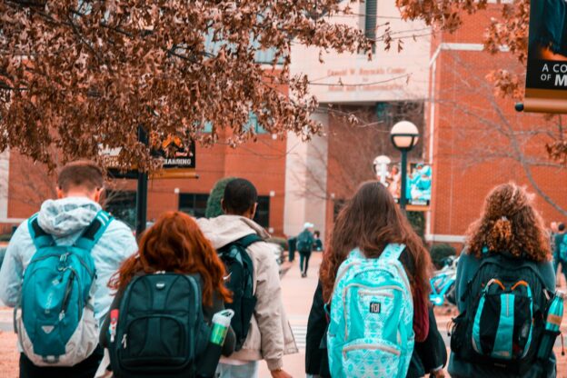 Four students walking towards the college entrance.